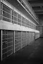 Monochrome image of an empty prison row with steel bars and walkways.