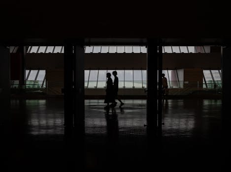 Silhouette of people walking through a modern hallway with large windows in Shanghai, China.