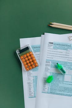 1040 tax forms with calculator, pencils, and markers on green surface.