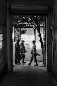 Monochrome image of pedestrians walking through a city gateway, capturing a candid urban moment.