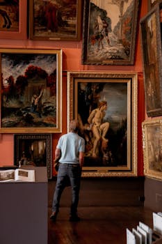 pexels-photo-18631363-18631363 Man stands observing classic paintings in a Paris museum art gallery.