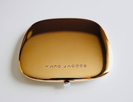 Close-up of a luxurious golden compact on a white surface, showcasing elegance and style.