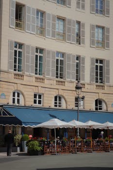 A classic Parisian building with a charming outdoor cafe, perfect for travel and urban themes.