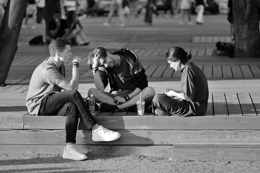 pexels-photo-17875554-17875554 Three young adults sitting on a bench chatting in a vibrant urban setting.