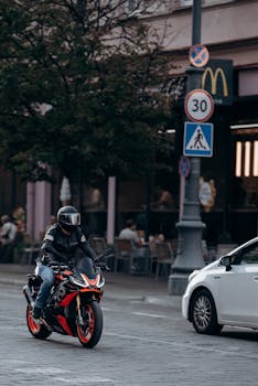 Motorcyclist riding through city street with traffic signs and buildings.