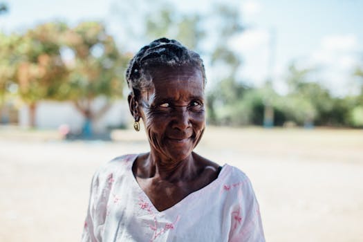 Charming portrait of an elderly woman smiling warmly in a sunny outdoor setting.