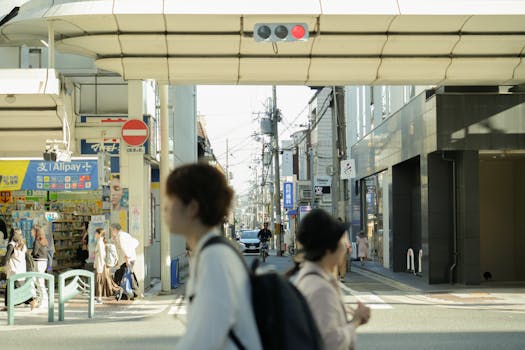 Busy street scene in Japan with pedestrians, shops, and traffic under daylight.