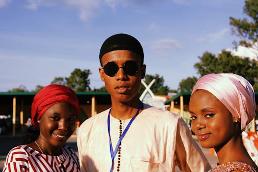 Group of friends smiling outdoors in traditional attire during a summer sunset.