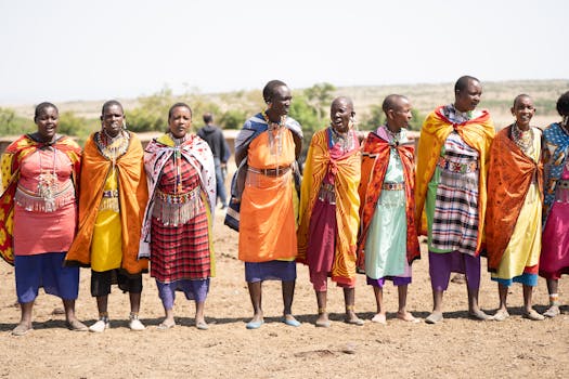 A group of Maasai people in traditional attire celebrating in the Kenyan plains.