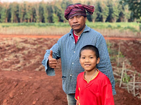 Father and son bonding in the fields of rural Isan, Thailand, showcasing traditional life.