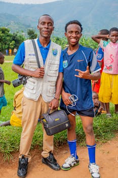 Two men enjoying a sunny day at a soccer event in a mountainous region.