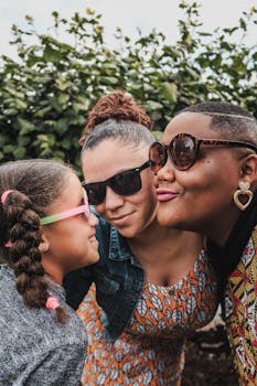 Three smiling family members enjoy a sunny day outdoors wearing stylish sunglasses.